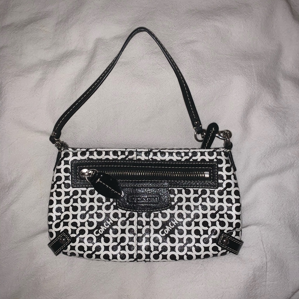 Coach signature-canvas baguette bag in black and white, photographed flat with the short shoulder strap laid out